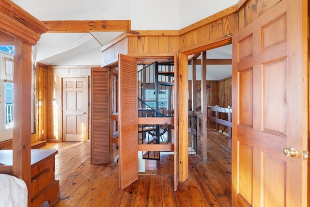 hallway with wood-type flooring, wooden walls, and beam ceiling