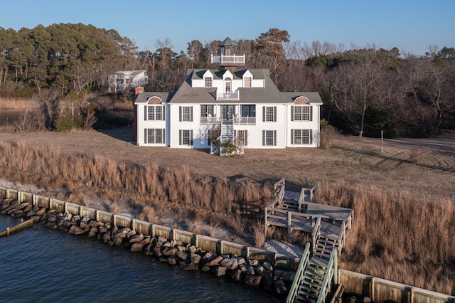 rear view of house featuring a water view and a balcony