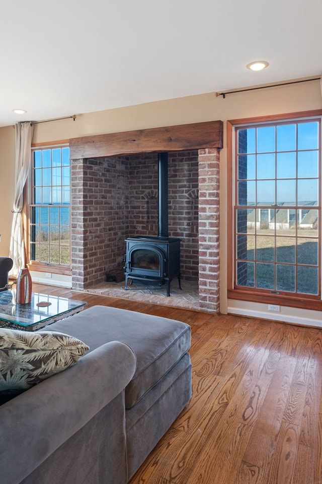 living room with a wood stove, light hardwood / wood-style flooring, and a water view