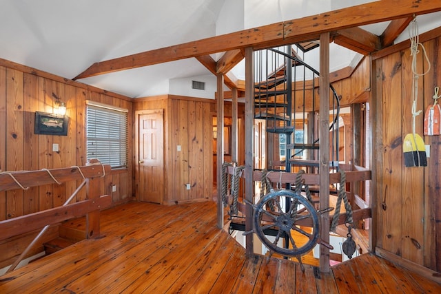 interior space featuring wood-type flooring, lofted ceiling with beams, and wooden walls