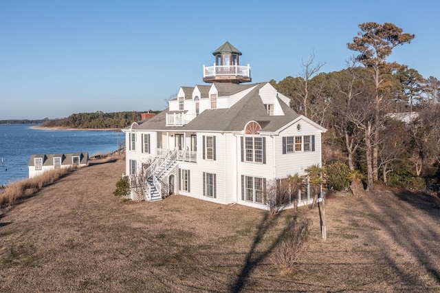 back of house with a lawn, a water view, and a balcony