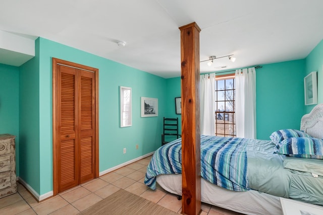 bedroom featuring track lighting, light tile patterned flooring, and a closet