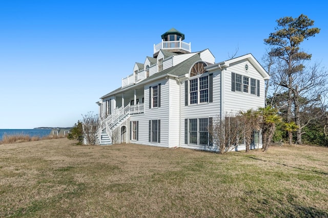 rear view of house with a yard and a balcony