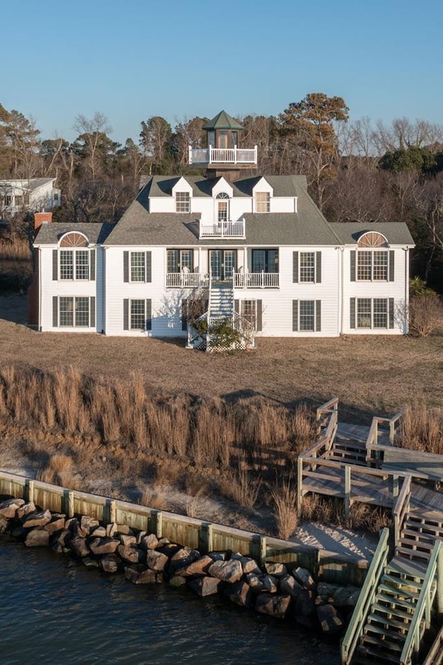 rear view of property featuring a water view and a balcony