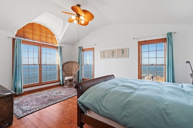 bedroom with multiple windows, ceiling fan, a water view, and hardwood / wood-style flooring