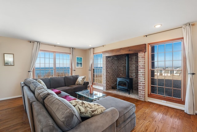 living room featuring a wood stove, a water view, and wood-type flooring