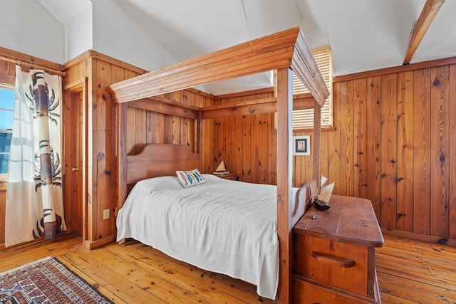 bedroom featuring hardwood / wood-style floors, lofted ceiling, and wooden walls