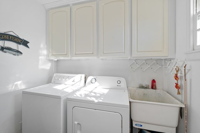 clothes washing area featuring washer and clothes dryer, cabinets, and sink