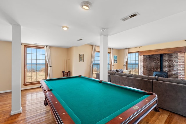 playroom with a wood stove, pool table, a water view, and hardwood / wood-style flooring