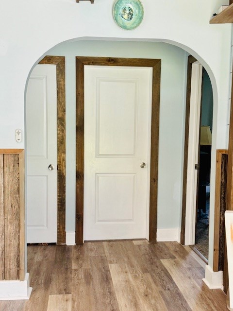 hall featuring arched walkways and wood finished floors