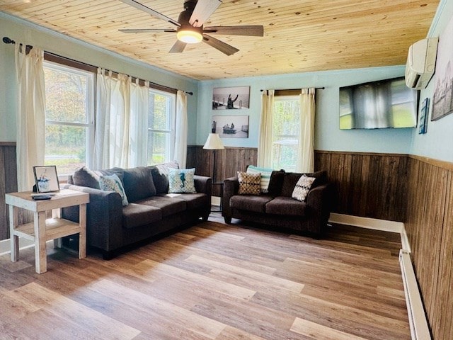living room with a baseboard heating unit, plenty of natural light, a wall mounted AC, and ceiling fan