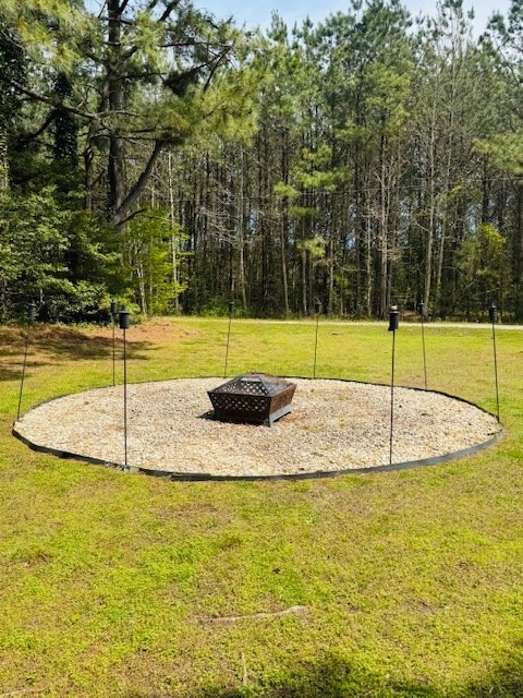 view of community with a lawn and an outdoor fire pit