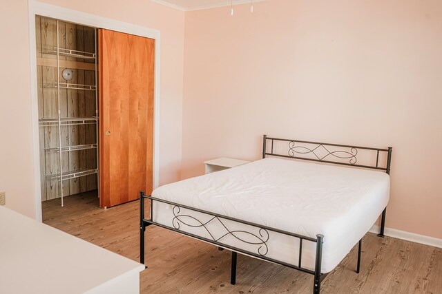 bedroom with hardwood / wood-style flooring, a closet, and crown molding