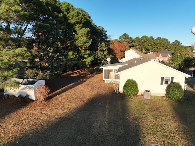 view of side of home with central air condition unit, a sunroom, and a lawn