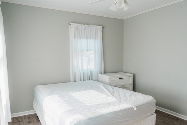 bedroom featuring dark hardwood / wood-style flooring, ceiling fan, and crown molding