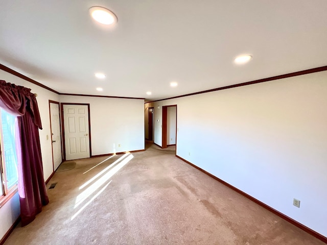 empty room featuring light colored carpet and crown molding