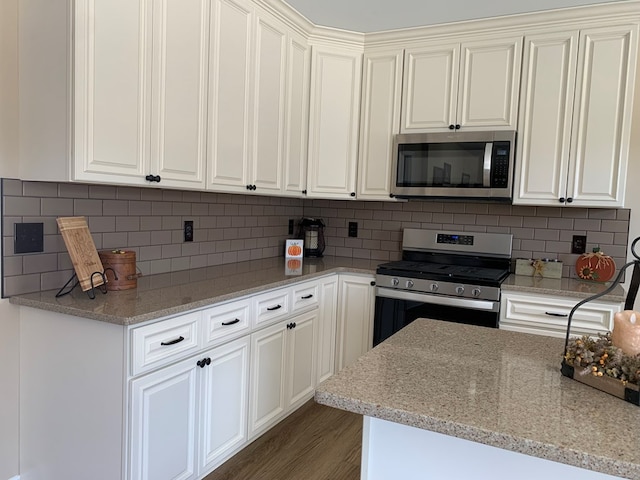 kitchen featuring dark hardwood / wood-style floors, appliances with stainless steel finishes, tasteful backsplash, light stone counters, and white cabinetry