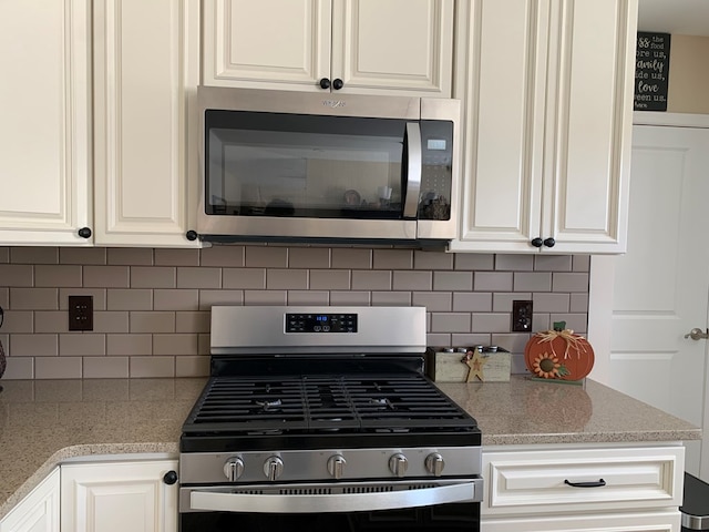 kitchen with tasteful backsplash, white cabinetry, and appliances with stainless steel finishes