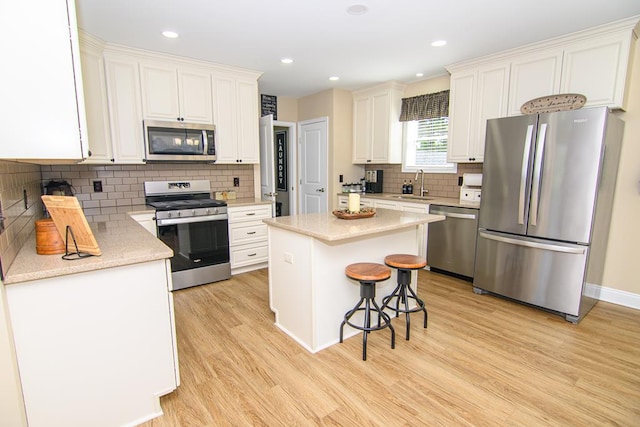2265 Yardarm Dr, Greenbackville, VA 23356 - kitchen featuring light wood-style floors, a center island, tasteful backsplash, a sink, and appliances with stainless steel finishes