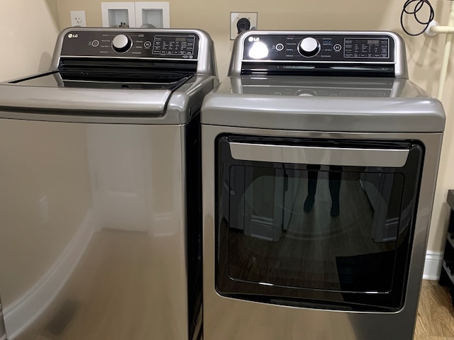 laundry room with wood-type flooring and separate washer and dryer