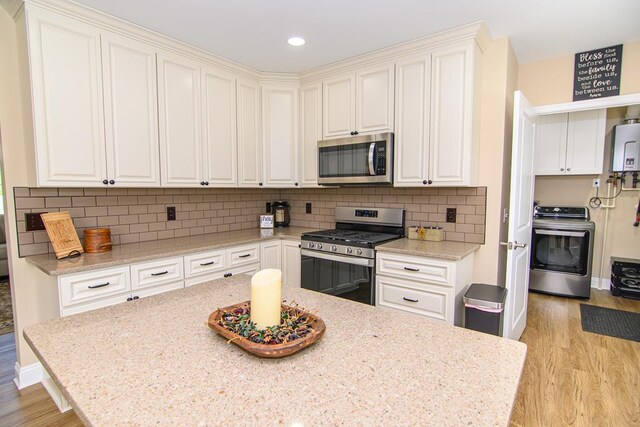2265 Yardarm Dr, Greenbackville, VA 23356 - kitchen with tasteful backsplash, stainless steel appliances, light wood-type flooring, and washer / clothes dryer