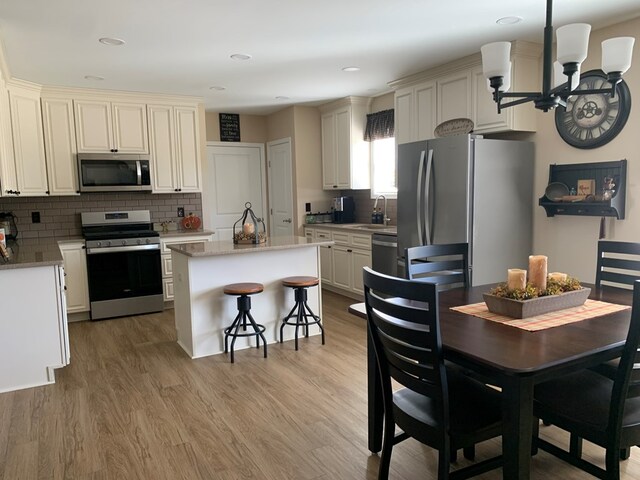 kitchen with sink, light hardwood / wood-style floors, tasteful backsplash, a kitchen island, and stainless steel appliances