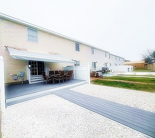 rear view of house with fence and a deck