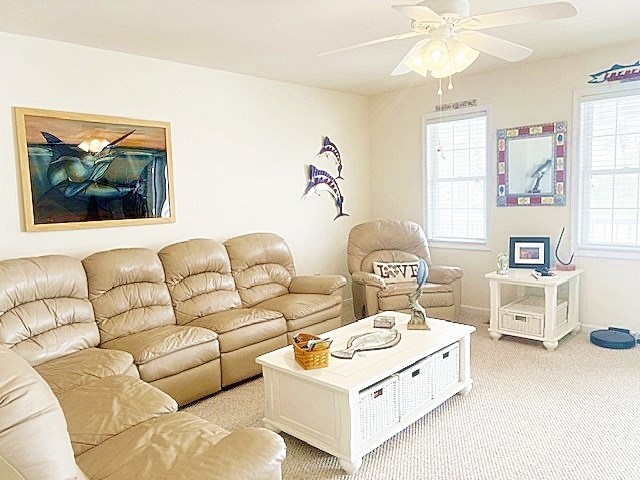 living area featuring light colored carpet, ceiling fan, and baseboards