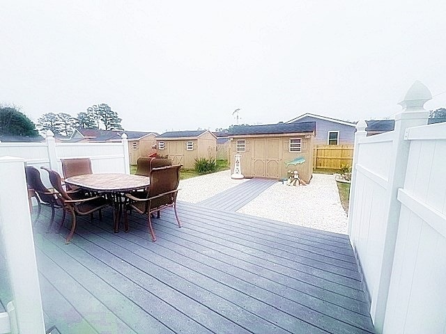 deck featuring outdoor dining area, an outdoor structure, and a shed