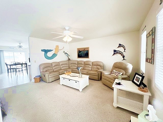 living area featuring a ceiling fan and carpet