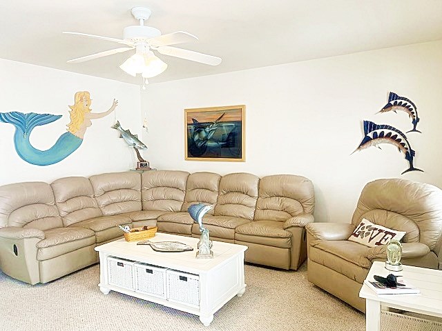 living area featuring light carpet and ceiling fan