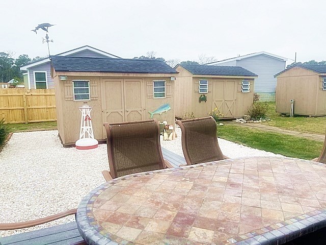 view of patio featuring an outbuilding, fence, and a storage shed