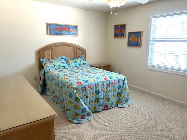 bedroom with a ceiling fan, carpet flooring, and baseboards