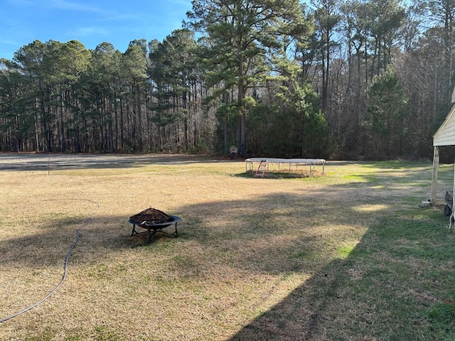 view of yard with a trampoline and a fire pit