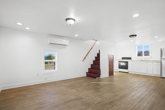 unfurnished living room featuring wood-type flooring, sink, and an AC wall unit