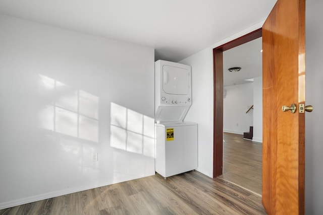 laundry area featuring wood-type flooring and stacked washer / drying machine