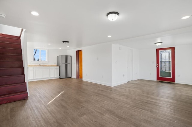 unfurnished living room featuring hardwood / wood-style flooring, sink, and a wealth of natural light