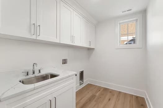 laundry room featuring cabinets, washer hookup, hookup for an electric dryer, sink, and light hardwood / wood-style floors