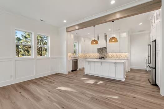 kitchen featuring white cabinets, decorative backsplash, stainless steel appliances, and hanging light fixtures