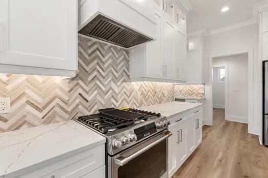 kitchen with stainless steel range with gas cooktop, white cabinets, and custom range hood