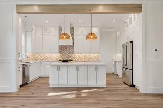 kitchen featuring light wood-type flooring, stainless steel appliances, decorative light fixtures, white cabinets, and a center island