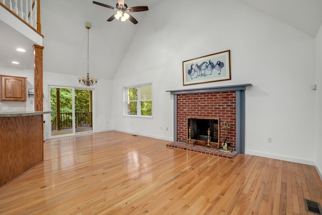 3315 Seaside Rd, Exmore, VA 23350 - unfurnished living room featuring high vaulted ceiling, a fireplace, light wood-style floors, a chandelier, and baseboards