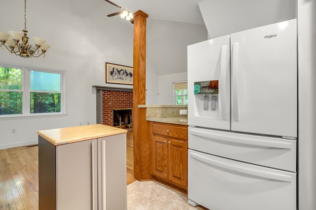 3315 Seaside Rd, Exmore, VA 23350 - kitchen featuring white fridge with ice dispenser, a center island, a chandelier, a fireplace, and light wood-type flooring