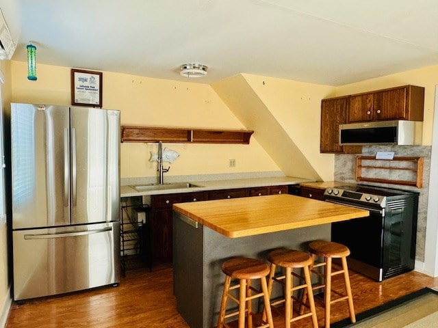 kitchen featuring wooden counters, backsplash, a breakfast bar, stainless steel appliances, and sink