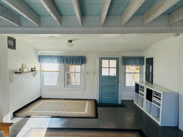 entrance foyer with beam ceiling, wooden walls, and a healthy amount of sunlight