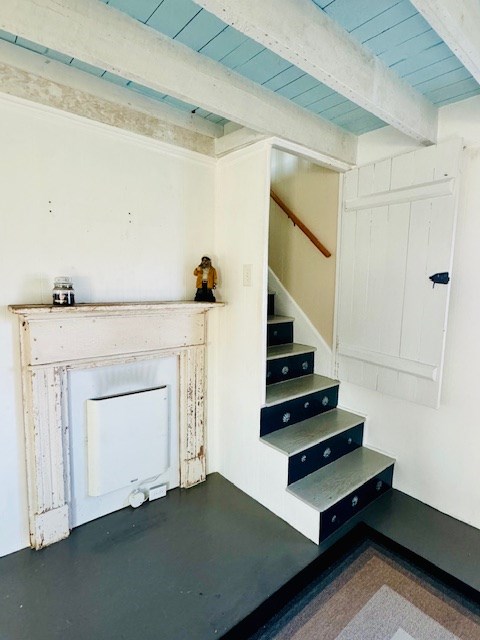 stairway featuring beamed ceiling, wood ceiling, and concrete floors