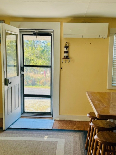 doorway to outside featuring hardwood / wood-style flooring and a wall mounted AC