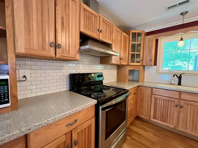 kitchen featuring stainless steel range with electric stovetop, sink, decorative backsplash, range hood, and light stone counters