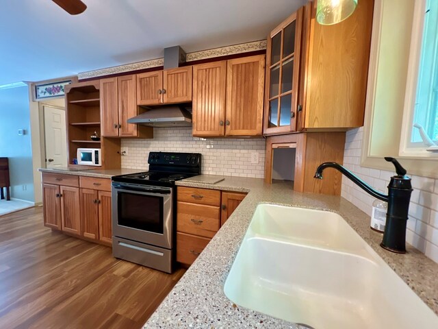 kitchen with backsplash, light stone countertops, stainless steel range, and sink