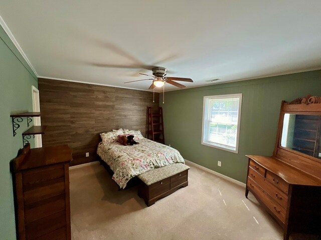 carpeted bedroom with wooden walls, ceiling fan, and ornamental molding